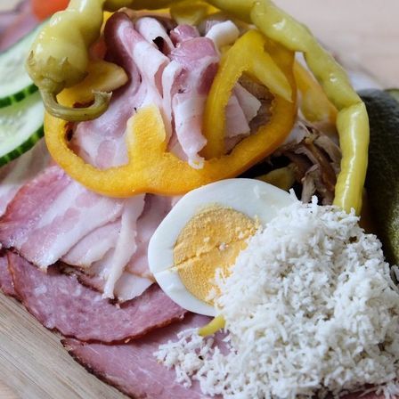 Ein Nahaufnahme einer Platte mit Schinken, geschnittenem Ei, gelben Paprika und Reis auf einer Holzoberfläche.