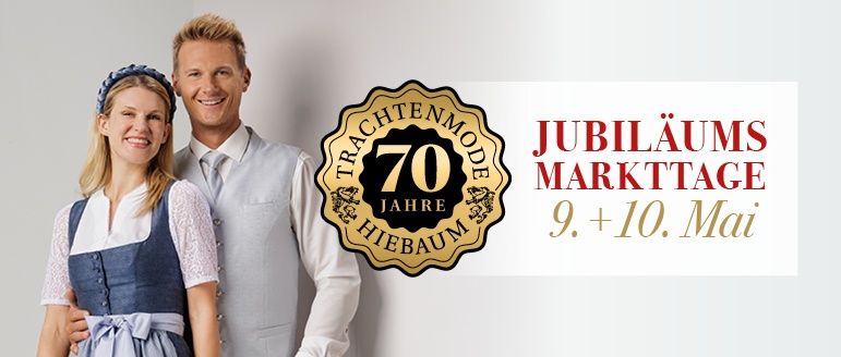 Ein Mann und eine Frau stehen nebeneinander. Sie lächeln und sind in traditioneller deutscher Kleidung gekleidet. Hinter ihnen befindet sich ein goldenes Abzeichen mit der Aufschrift 70 Jahre und ein weißer Banner mit der Aufschrift Jubilauums Marktage 9. + 10. Mai.