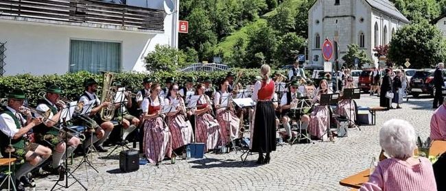 Eine Gruppe von Musikern spielt auf einer Kopfsteinpflasterstraße vor einer Kirche, während Menschen zuschauen.