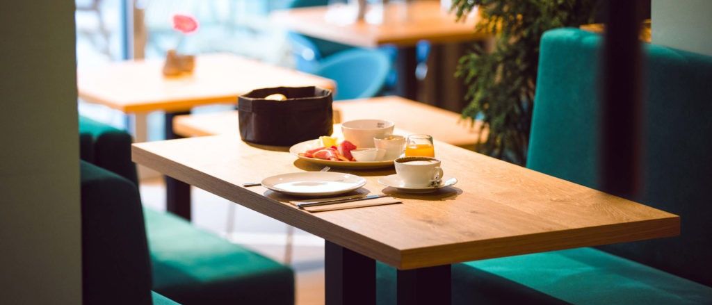 Ein Frühstückstisch in einem Restaurant mit einem Teller Obst, einer Tasse Kaffee und einem Glas Orangensaft.