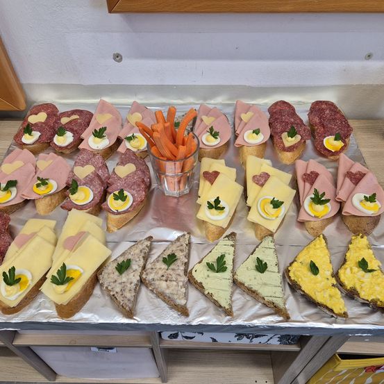 Ein Tablett mit einer Auswahl an Sandwiches, darunter Schinken, Käse und Ei, auf einem Tisch.