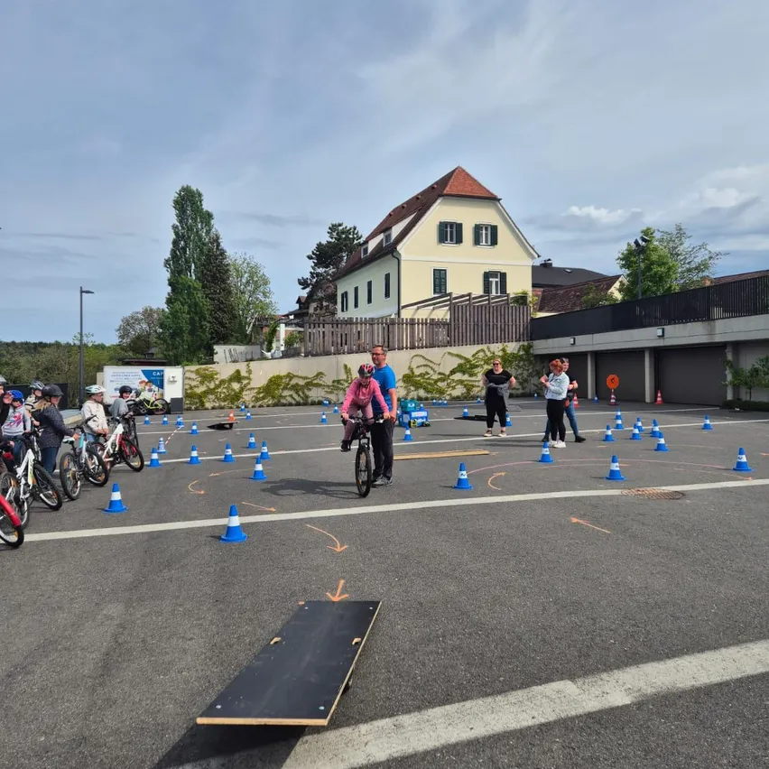 Eine Gruppe von Menschen fährt auf einem mit blauen Kegeln markierten Kurs im Freien auf Fahrrädern.