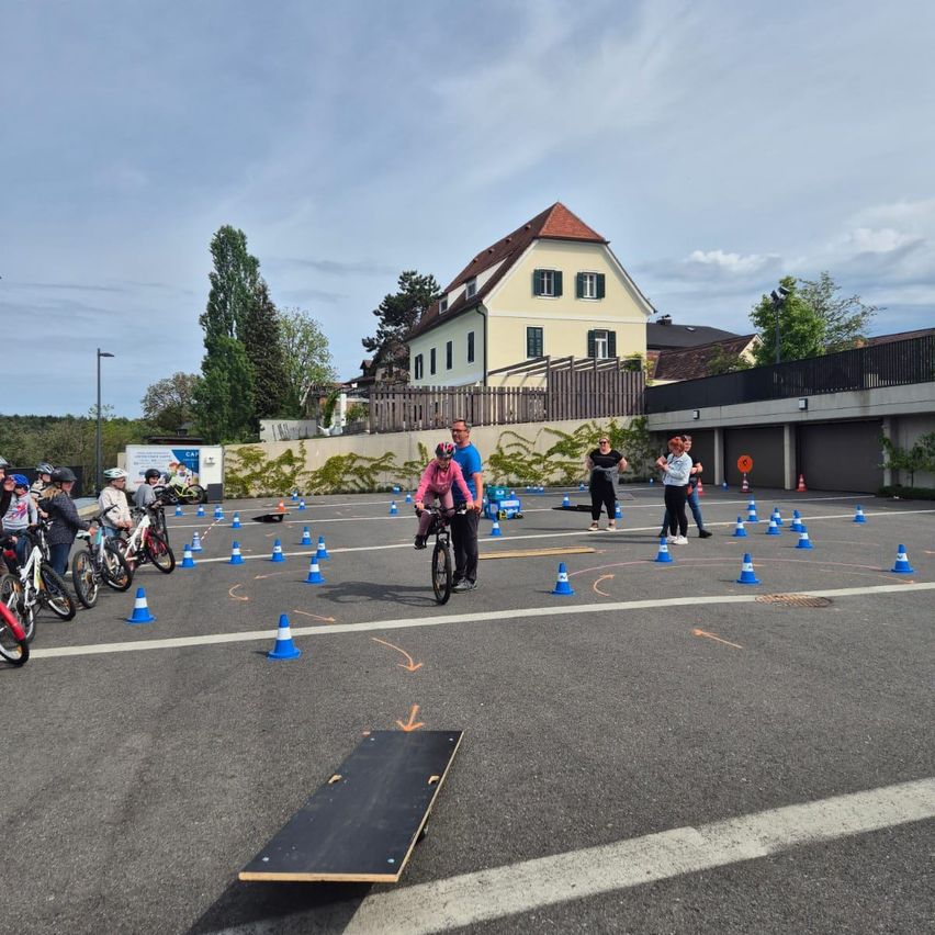 Eine Gruppe von Menschen fährt auf einem mit blauen Kegeln markierten Kurs im Freien auf Fahrrädern.