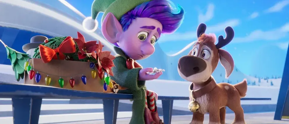 Ein farbenfroher animierter Elf sitzt auf einer Bank und hält ein kleines Objekt. Neben ihm steht ein Rentier mit einer Glocke. Der Hintergrund zeigt eine verschneite Szene mit Weihnachtsdekorationen.