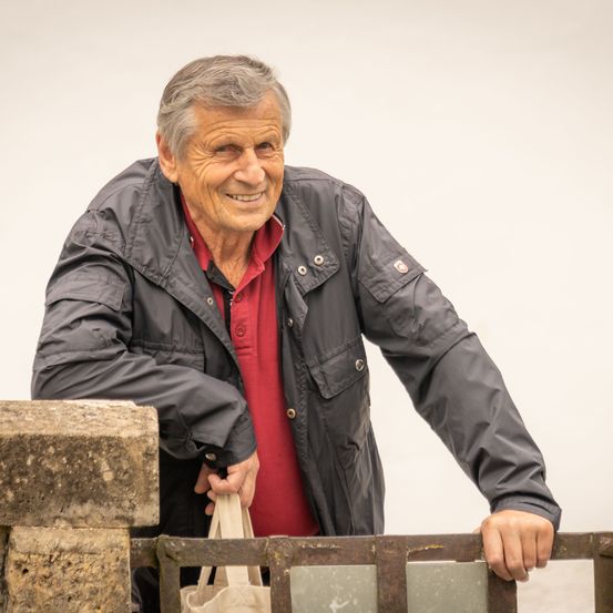 Bild enthält, Person, Senior Citizen, Head, Smile, Adult, Male, Man, Handrail, Coat, Jacket