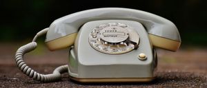 Ein altes weißes Wählscheibentelefon mit den Worten 'FEUER' und 'NOTRUF' darauf liegt auf dem Boden.