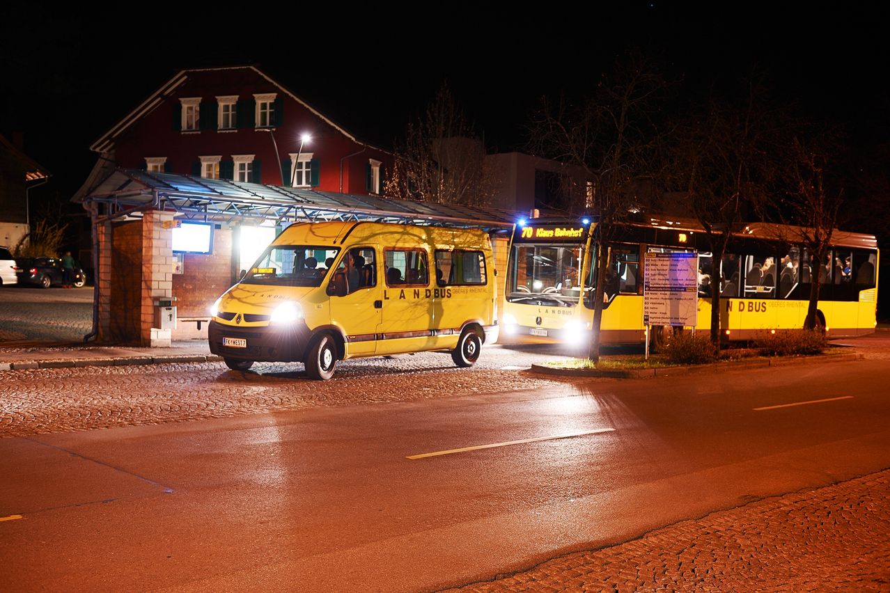 Ein gelber Bus mit der Aufschrift Landbus steht nachts am Straßenrand. Ein weiterer Bus ist daneben geparkt. Eine Straßenlaterne beleuchtet das Gebiet.