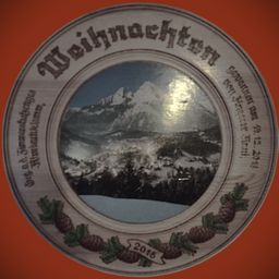 Ein dekorativer Teller mit einer verschneiten Berglandschaft, auf dem die Worte 'Weihnachten' und '2015' deutlich zu sehen sind, umgeben von Tannenzapfen.