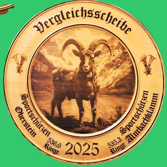 Eine goldene Scheibe mit einem Alpensteinbock in der Mitte und den Jahren 2025 und 536,6 darum herum. Der Hintergrund zeigt eine Gebirgslandschaft.