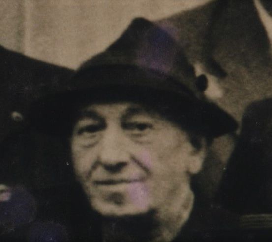 Ein altes Schwarz-Weiß-Foto eines lächelnden Mannes mit Hut und Hemd mit Kragen.