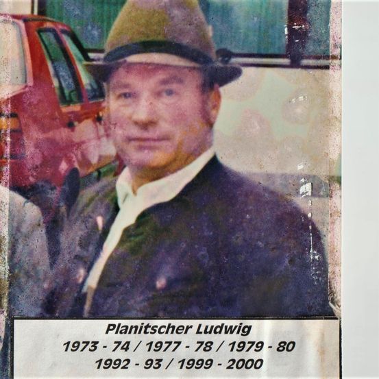 Ein altes Foto eines Mannes in Hut und Anzug. Ein rotes Auto ist im Hintergrund sichtbar. Der Mann heißt Ludwig Planitscher, mit den Jahren 1973-74, 1977-78, 1979-80, 1992-93 und 1999-2000 darunter aufgeführt.