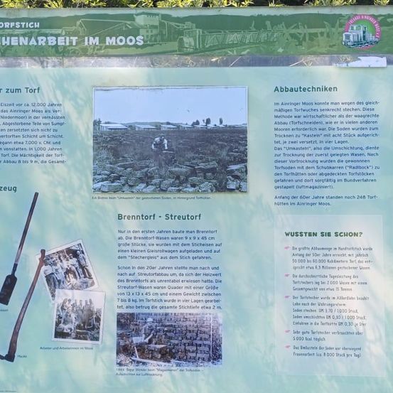 Das Schautafel am Eingang von Brenntorf-Streudorf erklärt die Geschichte der Torfgewinnung und deren Techniken. In den ersten Jahren wurden große Stöcke verwendet, um Torf zu entfernen, der dann in der Sonne getrocknet wurde. Im 20. Jahrhundert wurde Torf mit einer modernen Methode gewonnen, wobei Arbeiter eine Maschine benutzten, um Torf aus dem Boden zu extrahieren.