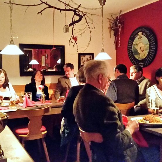 Eine Gruppe von Menschen sitzt um einen Tisch in einem Restaurant. Sie schauen auf ihre Handys und Teller mit Essen stehen vor ihnen.