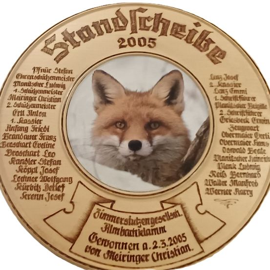 Eine goldfarbene runde Medaille zeigt ein Bild eines Fuchses. Namen umgeben den Fuchs, mit 'Standgericht' und '2005' darüber. 'Geboren am 2.3.2005 von Meiringer Christian' steht unter dem Fuchs.