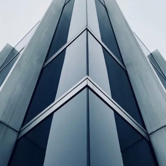 Nahaufnahme eines modernen Gebäudes mit reflektierenden Glaswänden und dreieckigem Design.