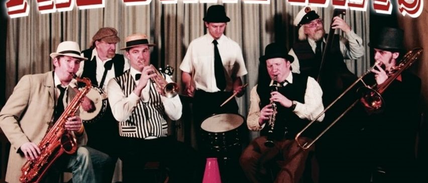 Eine Gruppe von Musikern in Vintage-Kleidung, die verschiedene Instrumente wie Saxophone, Trompeten und Posaunen spielen. Das Bild ist vor einem Hintergrund mit dem Text 'Dixieland Swing Hot Jazz'. Das Datum und die Uhrzeit der Veranstaltung sind ebenfalls angezeigt.