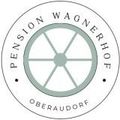 Ein kreisförmiges Logo für Pension Wagnerhof Oberaudorf, das ein stilisiertes Rad mit Speichen und einem grauen Kreis in der Mitte zeigt, umgeben von einem weißen Rand. Der Text ist in Schwarz geschrieben.
