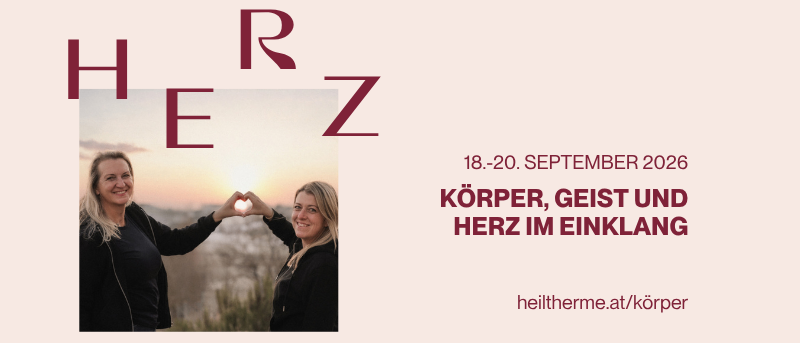 Zwei lächelnde Frauen bei Sonnenuntergang, eine macht ein Herz. Veranstaltung vom 18.-20. September 2026, Veranstaltungsname 'Körper, Geist und Herz im Einklang'. Webseite: heiltherme.at/korper.