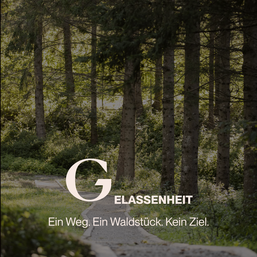 Ein Weg durch einen Wald mit hohen Bäumen und einem Schild, das 'GLASSENHEIT' und 'Ein Weg. Ein Waldstück. Kein Ziel.' in weißer Schrift zeigt.