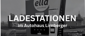 Ein Schwarz-Weiß-Foto zeigt eine Elektroauto-Ladestation mit 'ella'-Marke. Sie ist vor einem verschwommenen Hintergrund mit einem Gebäude und Bäumen zu sehen. Die Station zeigt 'LADESTATIONEN' und 'im Autohaus Lirnberger' Text.