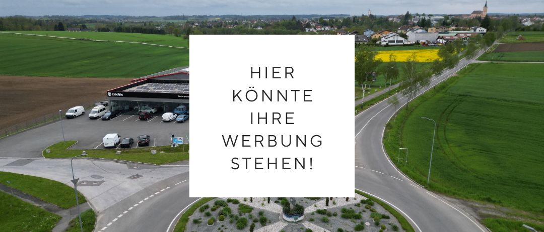 Ein Luftbild eines Parkplatzes mit geparkten Autos und einer Straße, an der ein Auto vorbeifährt. Ein weißer Kasten mit Text in der Mitte.