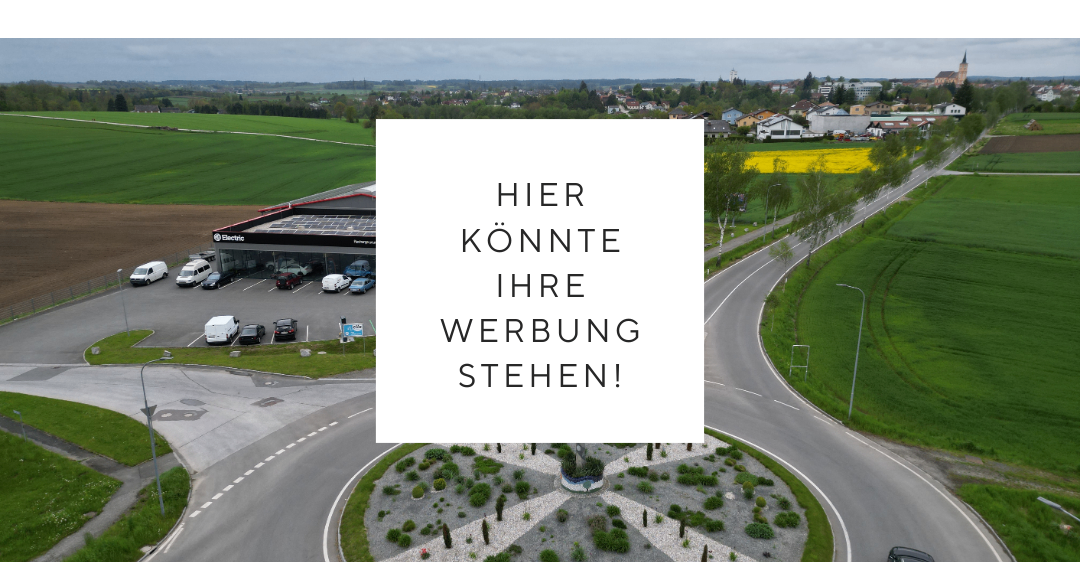 Ein Luftbild eines Parkplatzes mit geparkten Autos und einer Straße, an der ein Auto vorbeifährt. Ein weißer Kasten mit Text in der Mitte.