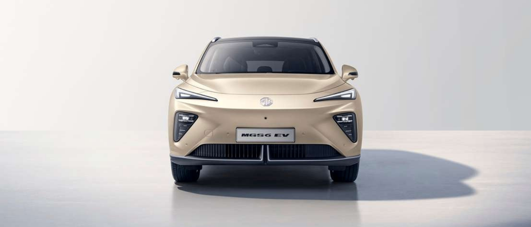 Die Vorderansicht eines beigefarbenen Elektroautos mit schlankem Design, LED-Scheinwerfern und MG-Logo auf der Kühlerhaube.