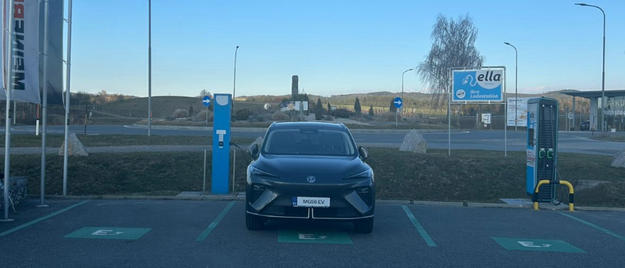 Ein schwarzer Elektrowagen wird an einer blauen Ladestation auf einem Parkplatz aufgeladen.