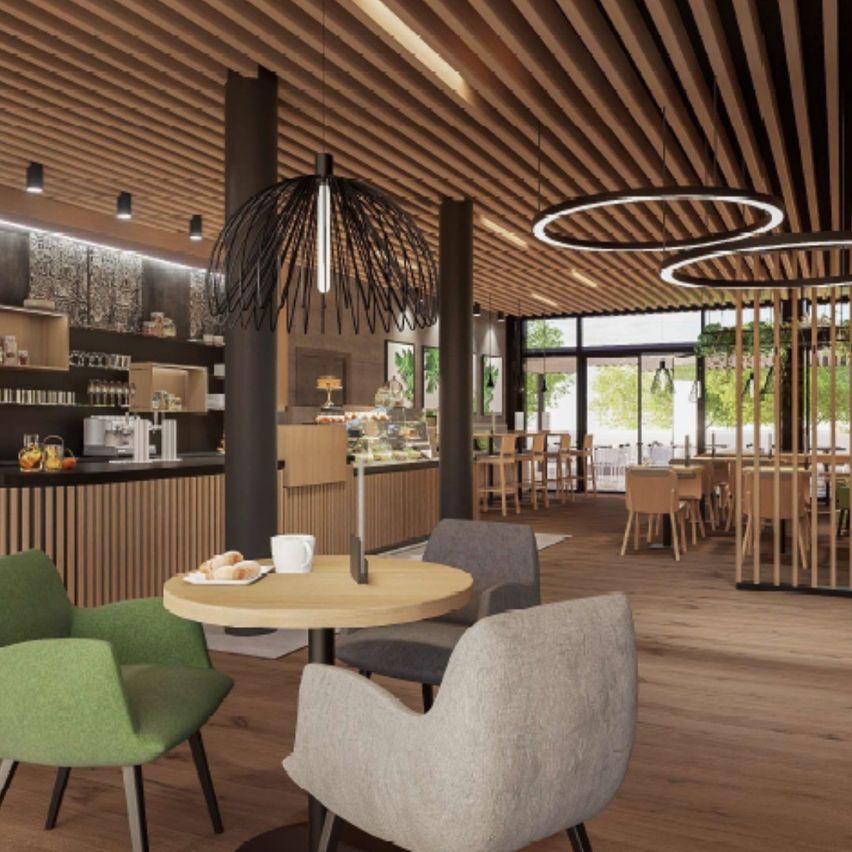 Ein Indoor-Café mit Holzböden, einem runden Tisch mit Tasse und Essen, Holzstühlen, einer Holztheke und Lampen, die von der Decke hängen.