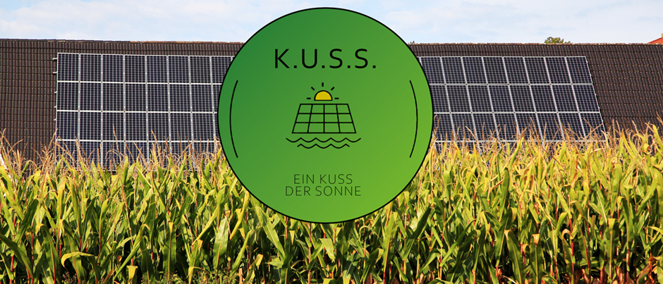 Ein grüner kreisförmiger Logo mit dem Text 'K.U.S.S.' ist vor einer Solarpanel-Anlage inmitten eines Maisfelds zu sehen.