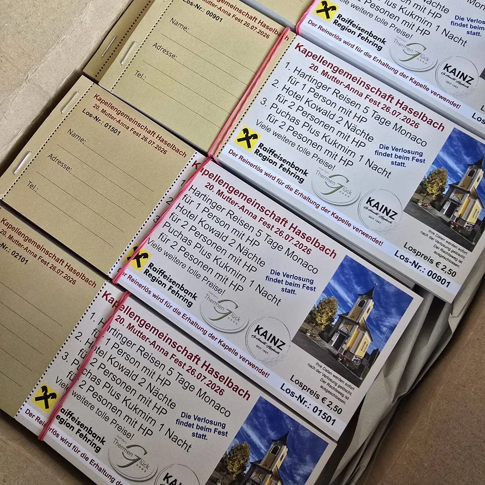 Eine Box mit mehreren Broschüren für Mutter-Anna-Fest 2026 in Haselbach. Die Broschüren enthalten Details über die Veranstaltungsdaten, Preise und die Raiffeisenbank Region Thermen.