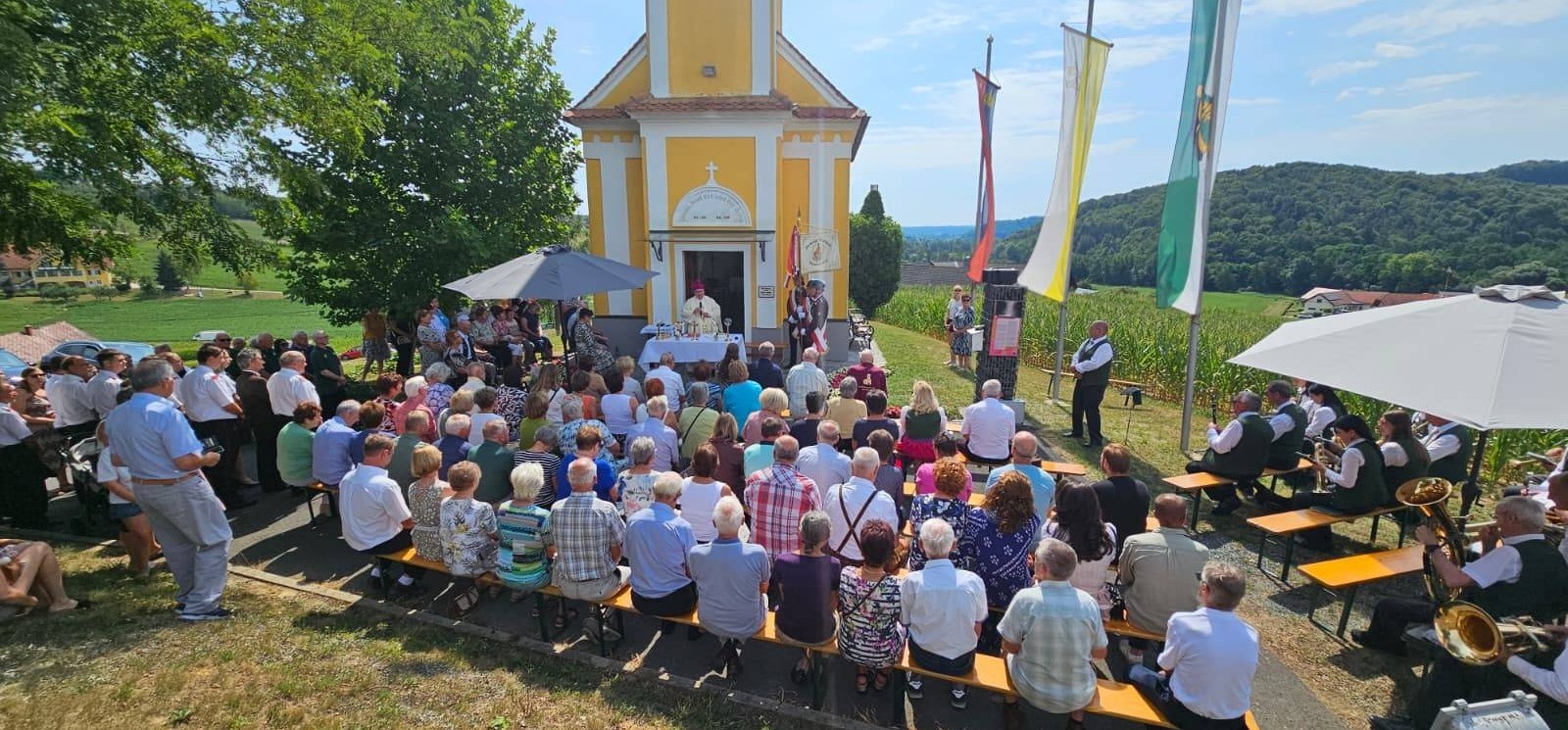 Gottesdienst vor gelber Kirche in Oberösterreich mit Bischof und Musikkapelle