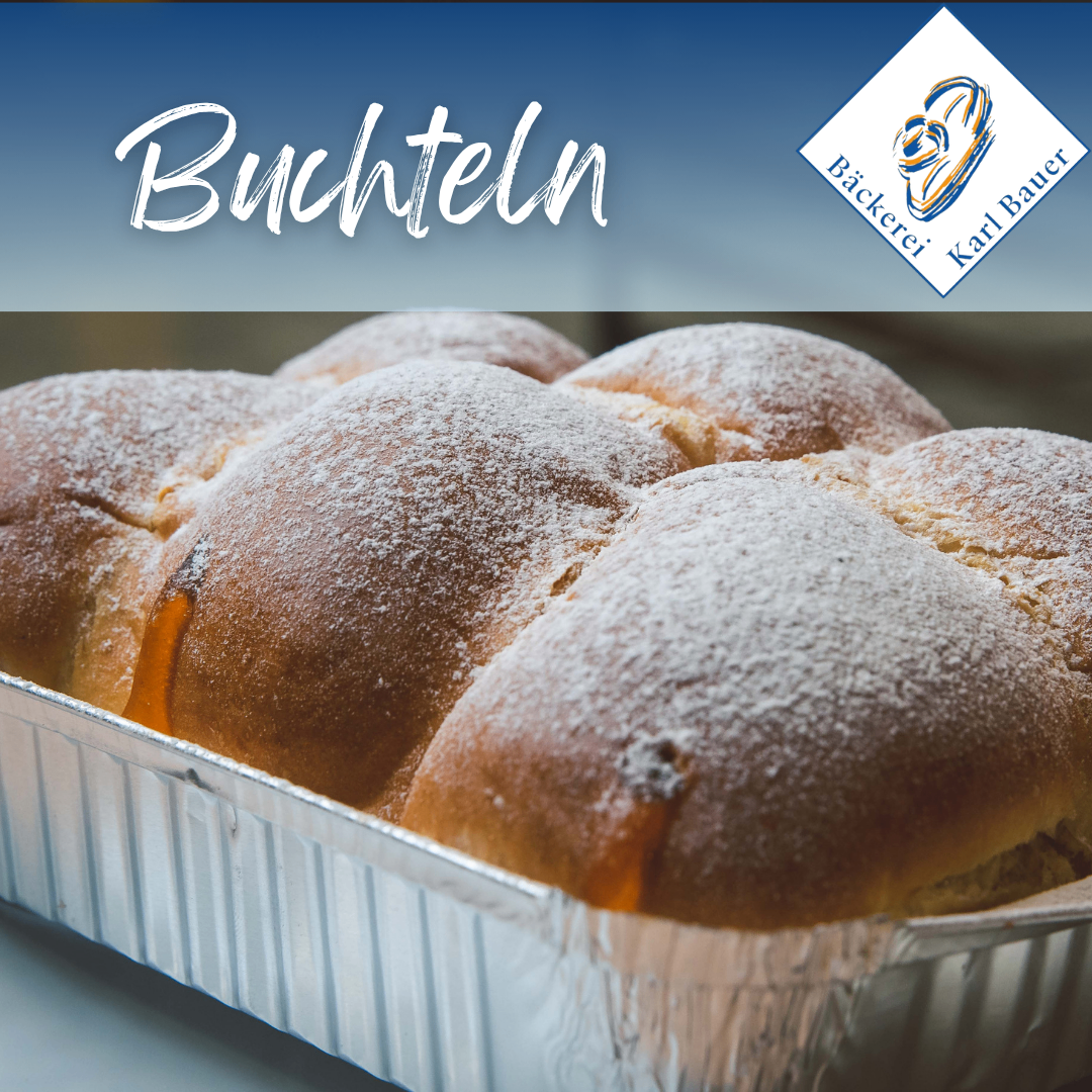 Ein Tablett mit Buchteln, einem traditionellen deutschen Gebäck, bestreut mit Puderzucker. Es ist in einer Bäckerei präsentiert.