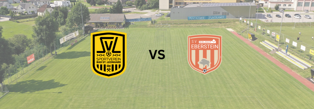 Eine Luftaufnahme eines Fußballfeldes mit zwei Logos darauf. Das linke Logo sagt 'SV Sportverein Bad St. Leonhard'. Das rechte Logo sagt 'SV DoloMit Eberstein'. Das Feld ist von Häusern und Bäumen umgeben.