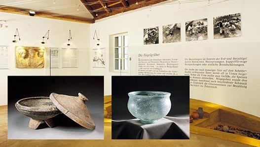 Ein Raum mit Artefakten und Ausstellungen. Ein Bild zeigt eine antike Schüssel und Deckel. Ein anderes zeigt eine Glasschale. Ein Bild einer Wand mit verschiedenen Bildern und Texten.