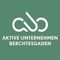 Ein grüner Hintergrund mit weißem Text und einem stilisierten Logo. Der Text lautet 'Aktive Unternehmen Berchtesgaden'. Das Logo besteht aus zwei überlappenden Buchstaben, die ein stilisiertes 'A' bilden.