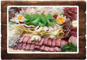 Eine Charcuterie-Platte mit Schinken, Käse, Radieschen, Eiern und Kräutern. Die Platte ist auf einer Holzoberfläche arrangiert.