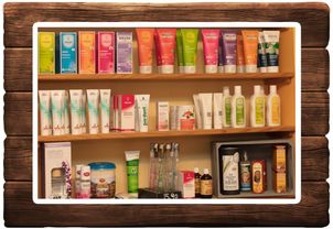 Ein hölzerne Regal zeigt eine Vielzahl von Hautpflegeprodukten, einschließlich Weleda Cremes, Lotionen und Pulver. Verschiedene Größen und Farben sind ordentlich angeordnet, einige in Behältern und andere in Schachteln. Ein Preisschild zeigt 15,90, und der Hintergrund ist weiß.