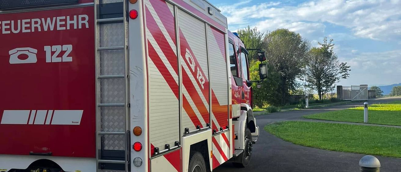 Ein roter Feuerwehrwagen mit der Nummer 122 ist auf einer Straße geparkt und zeigt die Notrufnummer 112 an.