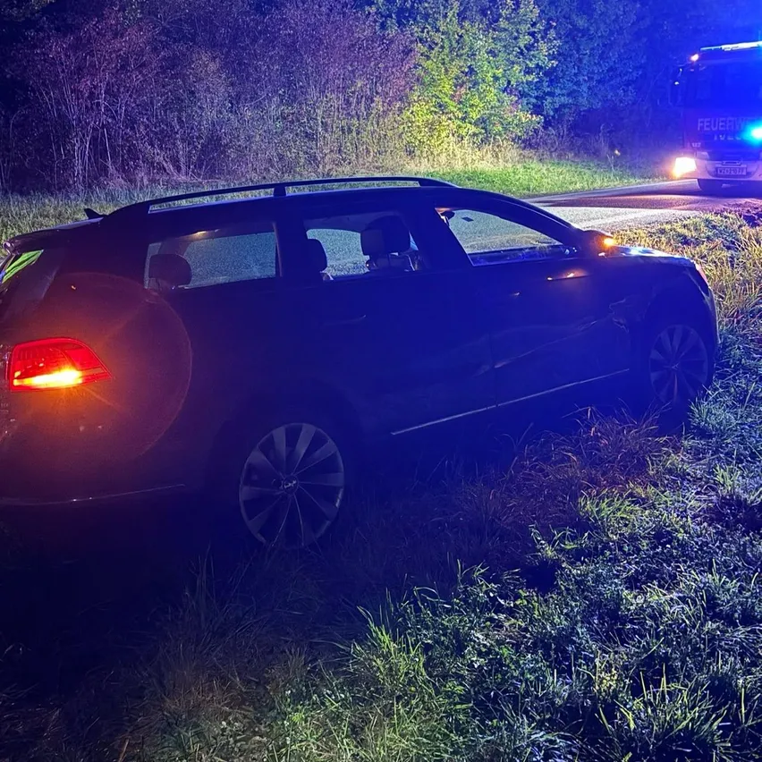 Ein dunkler SUV steht nachts am Straßenrand. Die Rücklichter des SUV sind eingeschaltet, und es scheint, dass er in einen Unfall verwickelt war.