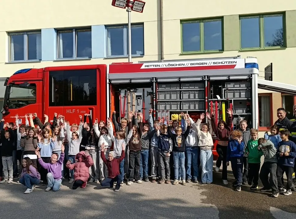 Eine Gruppe von Kindern und Erwachsenen posiert für ein Foto vor einem roten Feuerwehrauto.