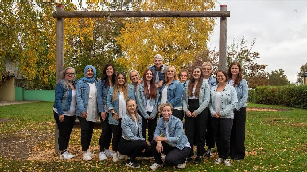 Eine Gruppe von Frauen posiert für ein Foto in einem Park mit einem hölzernen Bogen im Herbst.
