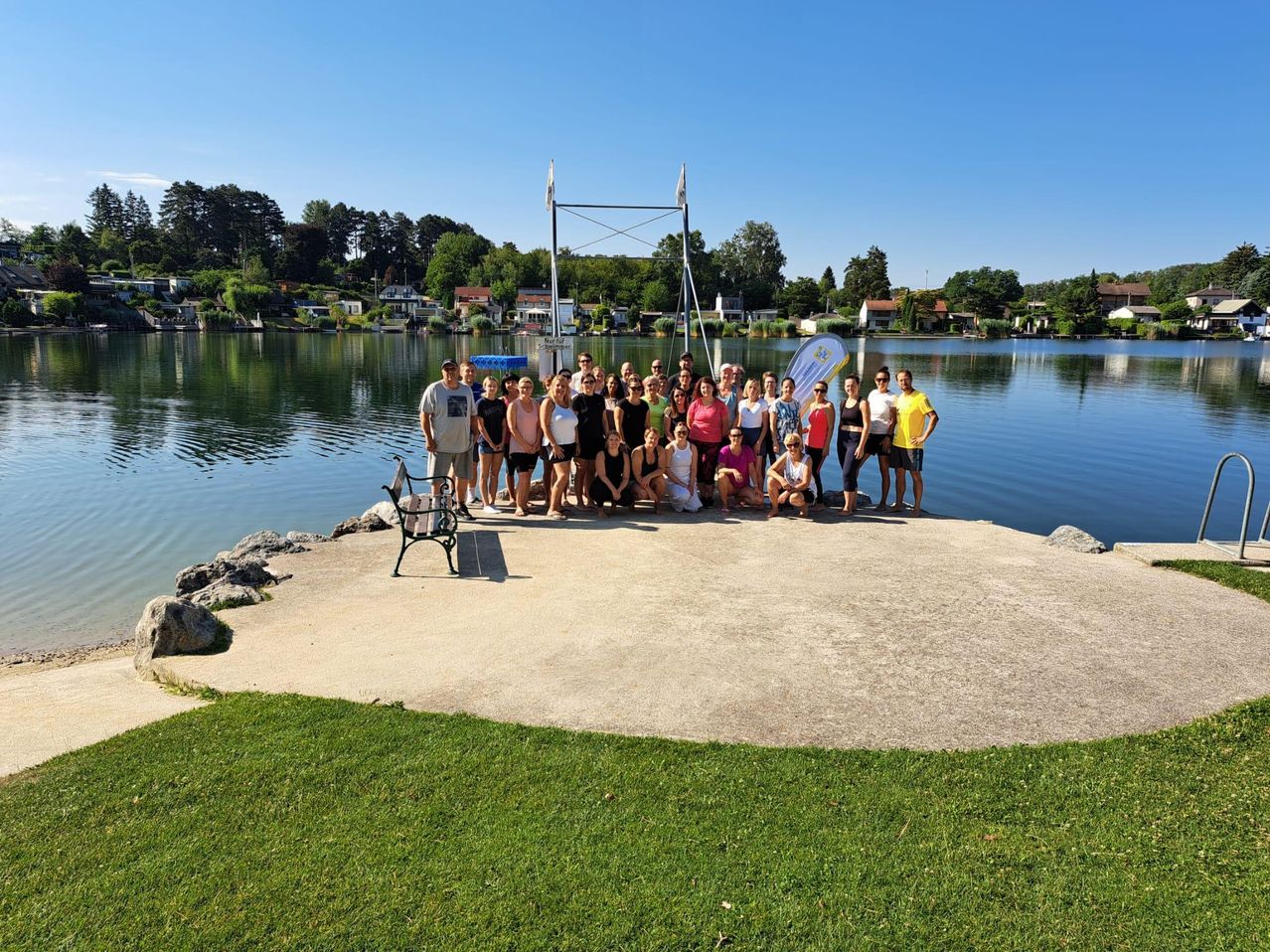 Eine Gruppe von Menschen versammelt sich auf einem Steg am See und posiert für ein Foto.