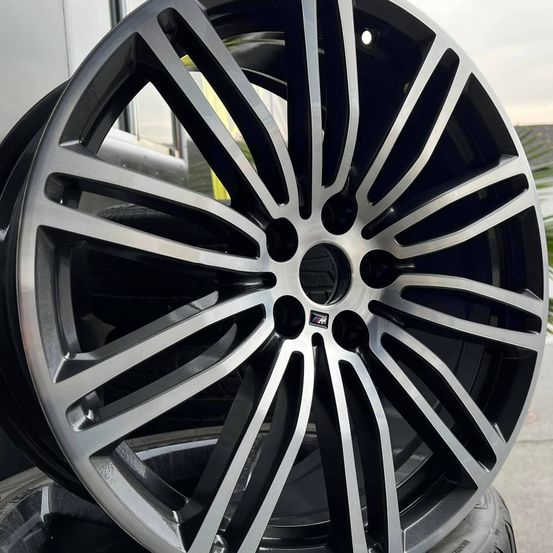 Nahaufnahme eines schwarzen und silbernen Alurads mit dem BMW-Logo. Die Speichen sind schlank und der Felgenrand ist poliert.