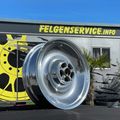 Ein glänzendes Chromrad wird vor einem Gebäude mit dem Text Felgenservice.info an der Wand ausgestellt. Ein gelbes Raddesign befindet sich auf der linken Seite des Gebäudes.