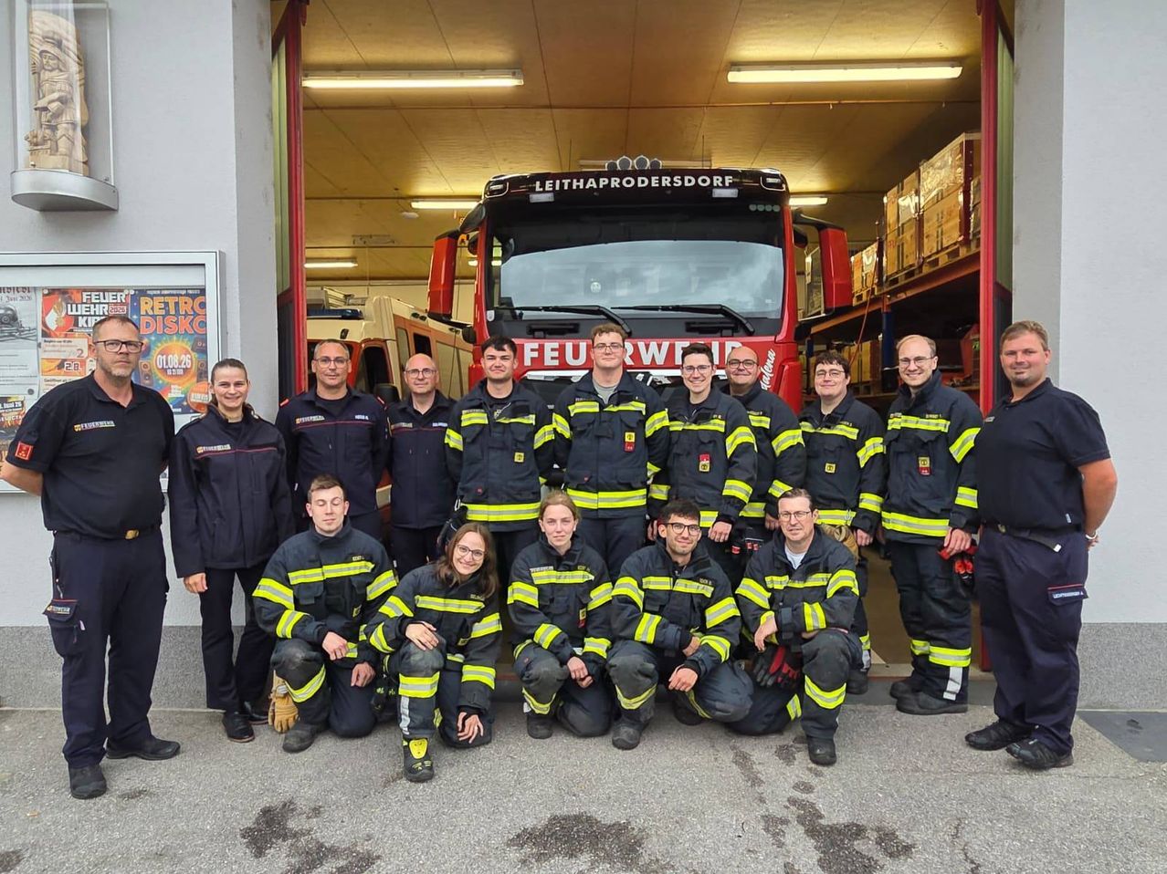 A group of firefighters in uniform pose for a photo in front of a fire truck.