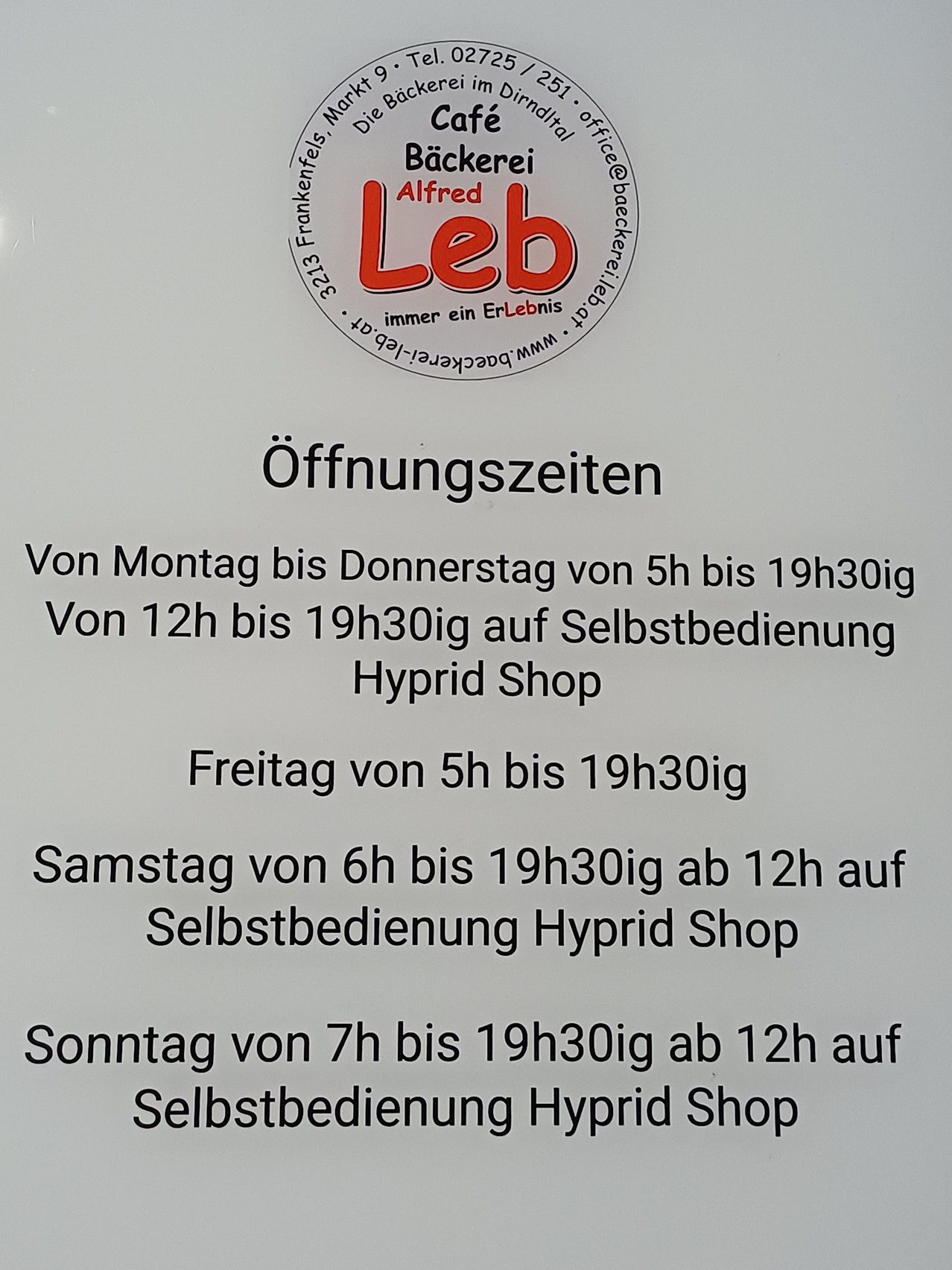 Ein Schild mit dem Logo 'Buckerel Alfred Leb' und Öffnungszeiten von Montag bis Sonntag, mit Hybrid-Shop-Selbstbedienung ab 12 Uhr.