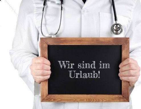Ein Arzt hält ein Tafel mit der Aufschrift 'Wir sind im Urlaub!' Er hat ein Stethoskop um den Hals.