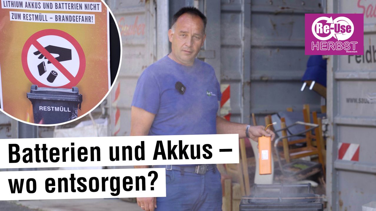 Ein Mann in einem blauen T-Shirt steht draußen mit einem Werkzeug in der Hand. Ein Schild sagt 'Nacht' und 'Rauch'. Ein anderes Schild sagt 'Batterie und Anschuldigungen?'