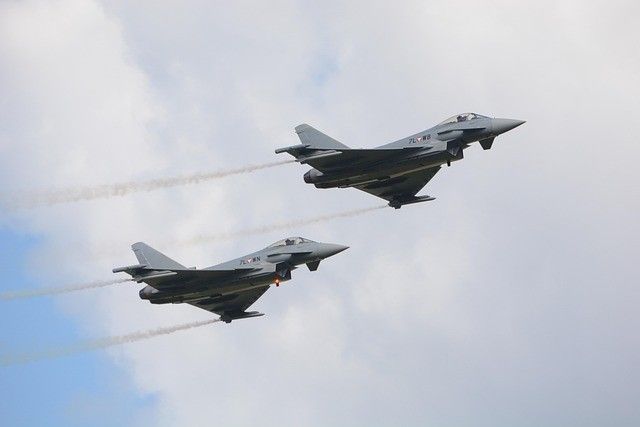 Zwei Militärjets fliegen mit Rauchspuren am Himmel. Ein Jet hat die Nummer 74 am Heck.
